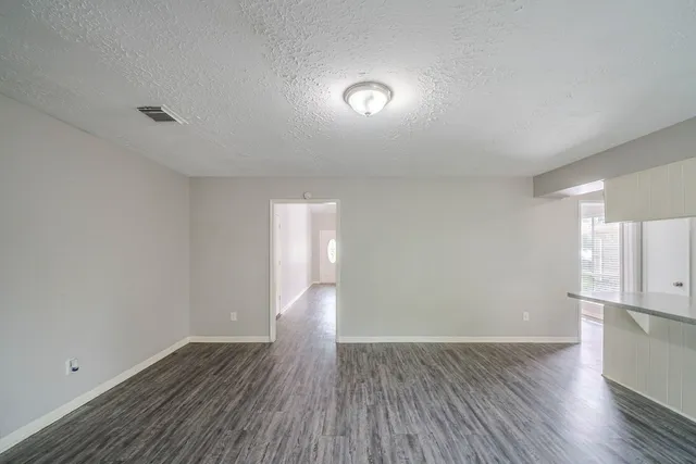 a view of empty room with wooden floor and window