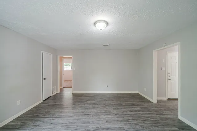 a view of an empty room with wooden floor and closet