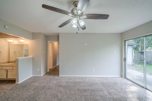 an empty room with a chandelier fan and windows