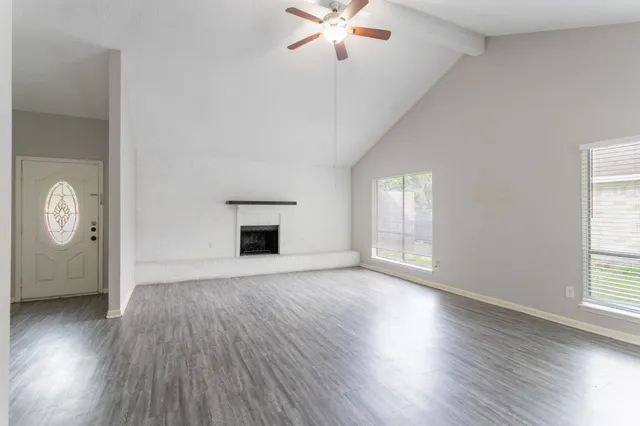a view of an empty room with window and wooden floor