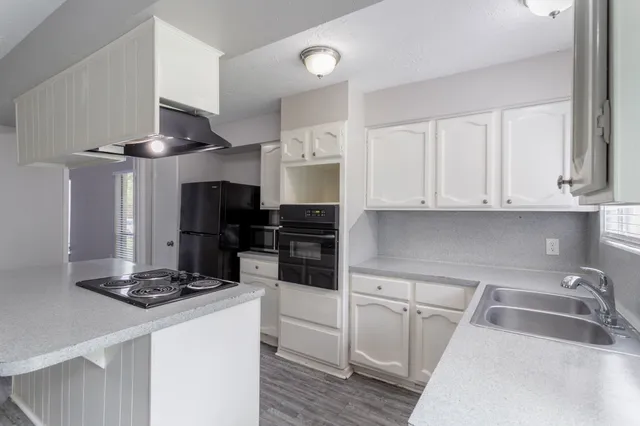 a kitchen with a refrigerator a stove a sink and a dining table with wooden floor