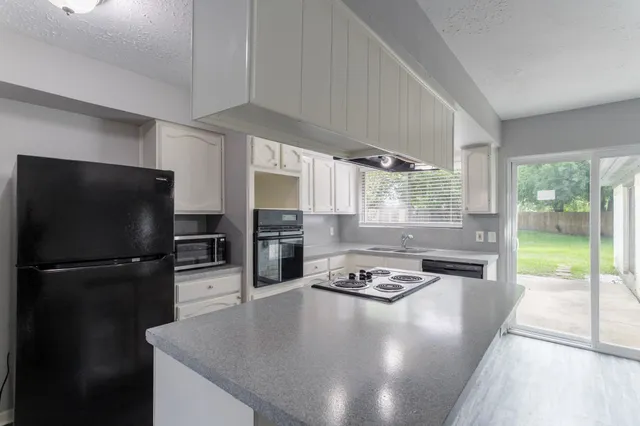 a kitchen with granite countertop a sink appliances wooden floor and cabinets