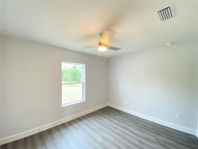 a view of an empty room and window and wooden floor