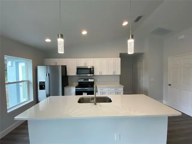 a large kitchen with stainless steel appliances a large counter top and wooden floors