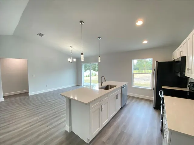 a large kitchen with kitchen island a sink dishwasher a stove and a refrigerator with wooden floor