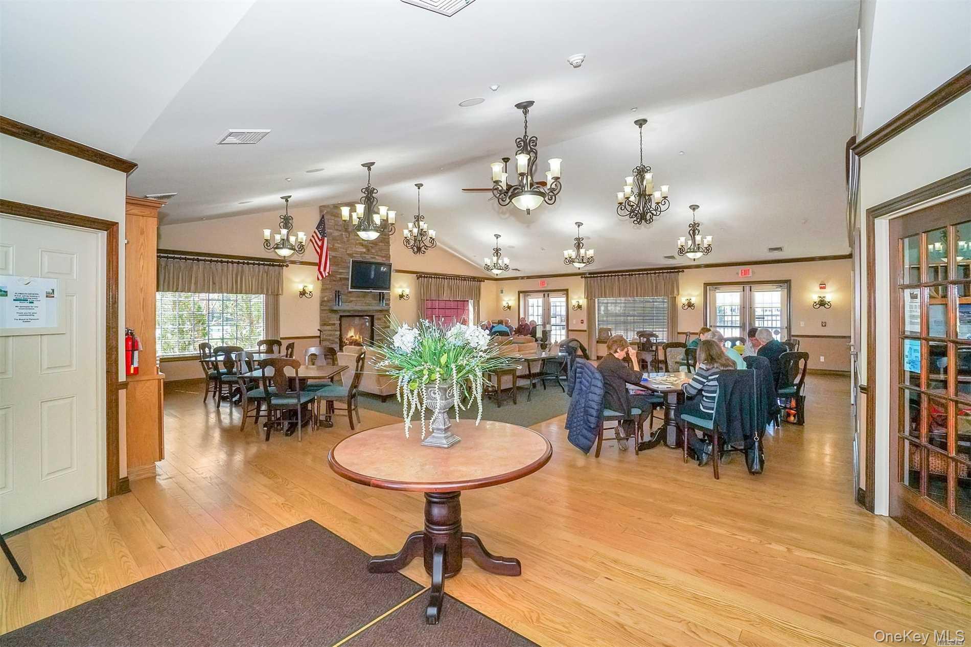 230 Ira Road, Unit 230 Mount Sinai, NY 11766 - Photo 30 of 38 a view of a dining room and livingroom with furniture wooden floor a chandelier