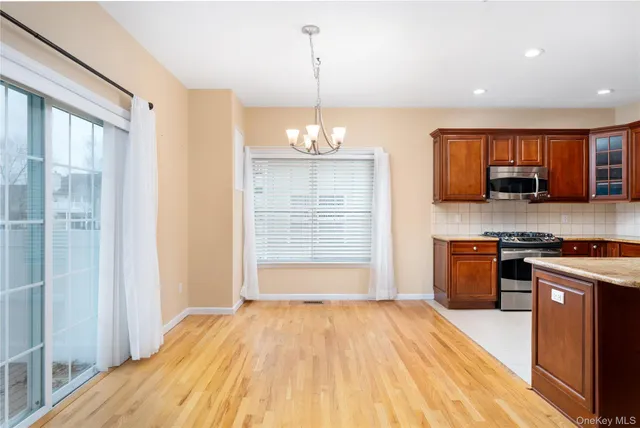 a open kitchen with stainless steel appliances granite countertop a stove top oven a sink dishwasher and a refrigerator with wooden floor