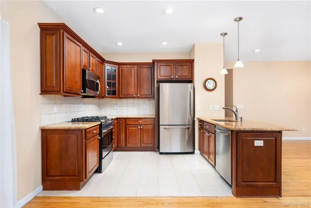 a kitchen with stainless steel appliances granite countertop a refrigerator a stove a sink and a microwave with wooden floor