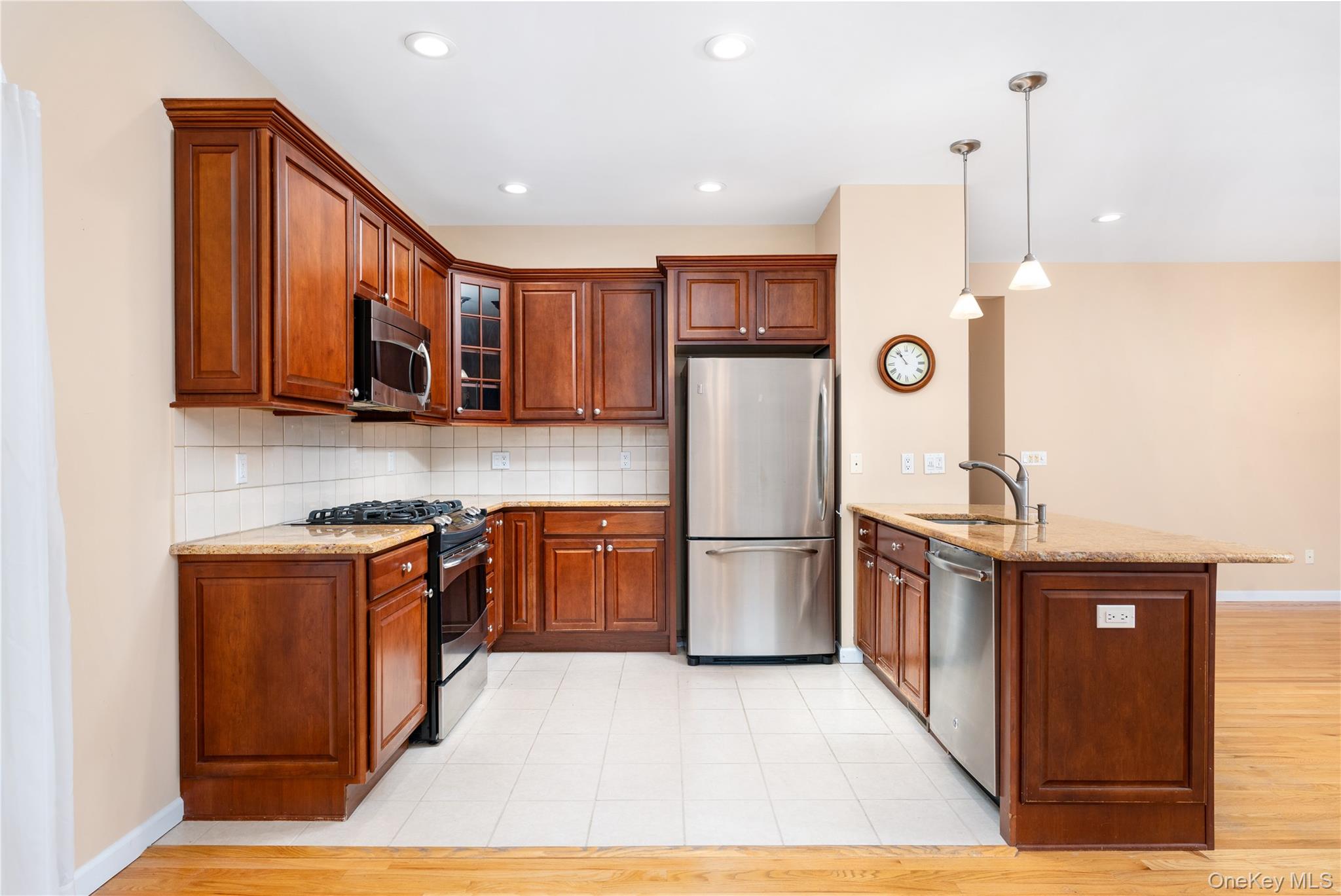 230 Ira Road, Unit 230 Mount Sinai, NY 11766 - Photo 9 of 38 a kitchen with stainless steel appliances granite countertop a refrigerator a stove a sink and a microwave with wooden floor
