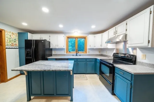 a kitchen with stainless steel appliances granite countertop a refrigerator a sink a stove and a refrigerator