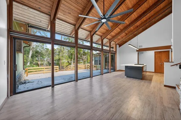 a hall with kitchen island stainless steel appliances wooden floor and large windows
