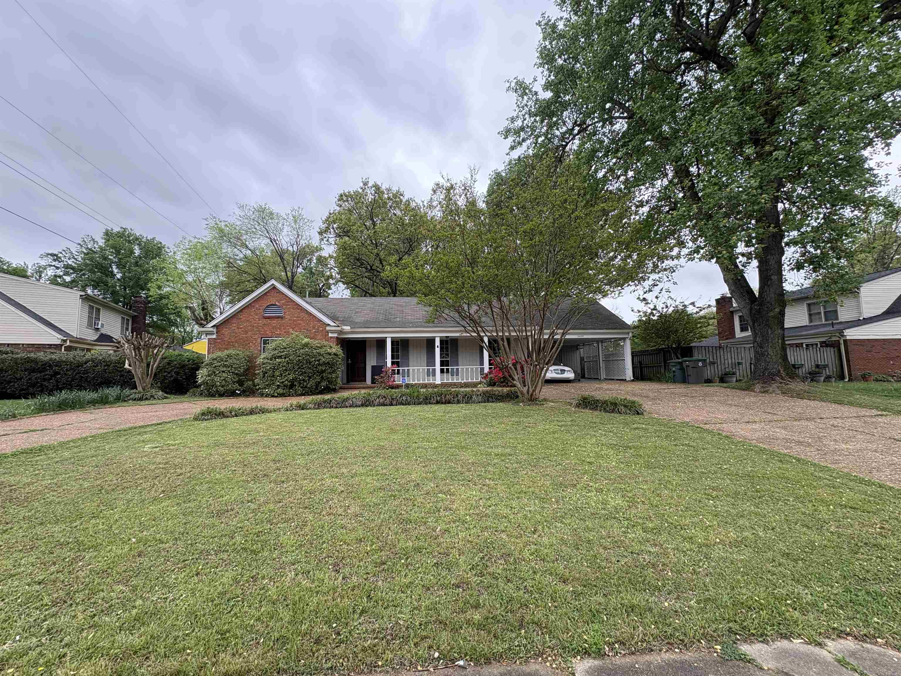 Single story home featuring a porch, a front lawn, concrete driveway, and a carport