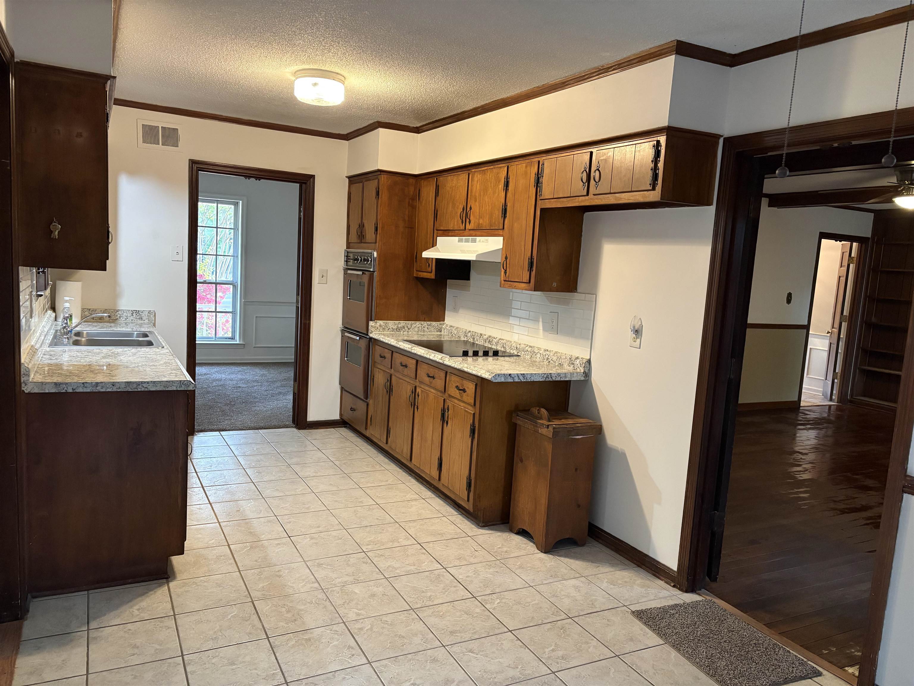5459 Knight Arnold Road Memphis, TN 38115 - Photo 12 of 38 Kitchen with a textured ceiling, crown molding, light tile patterned floors, tasteful backsplash, and dark wood finish cabinets