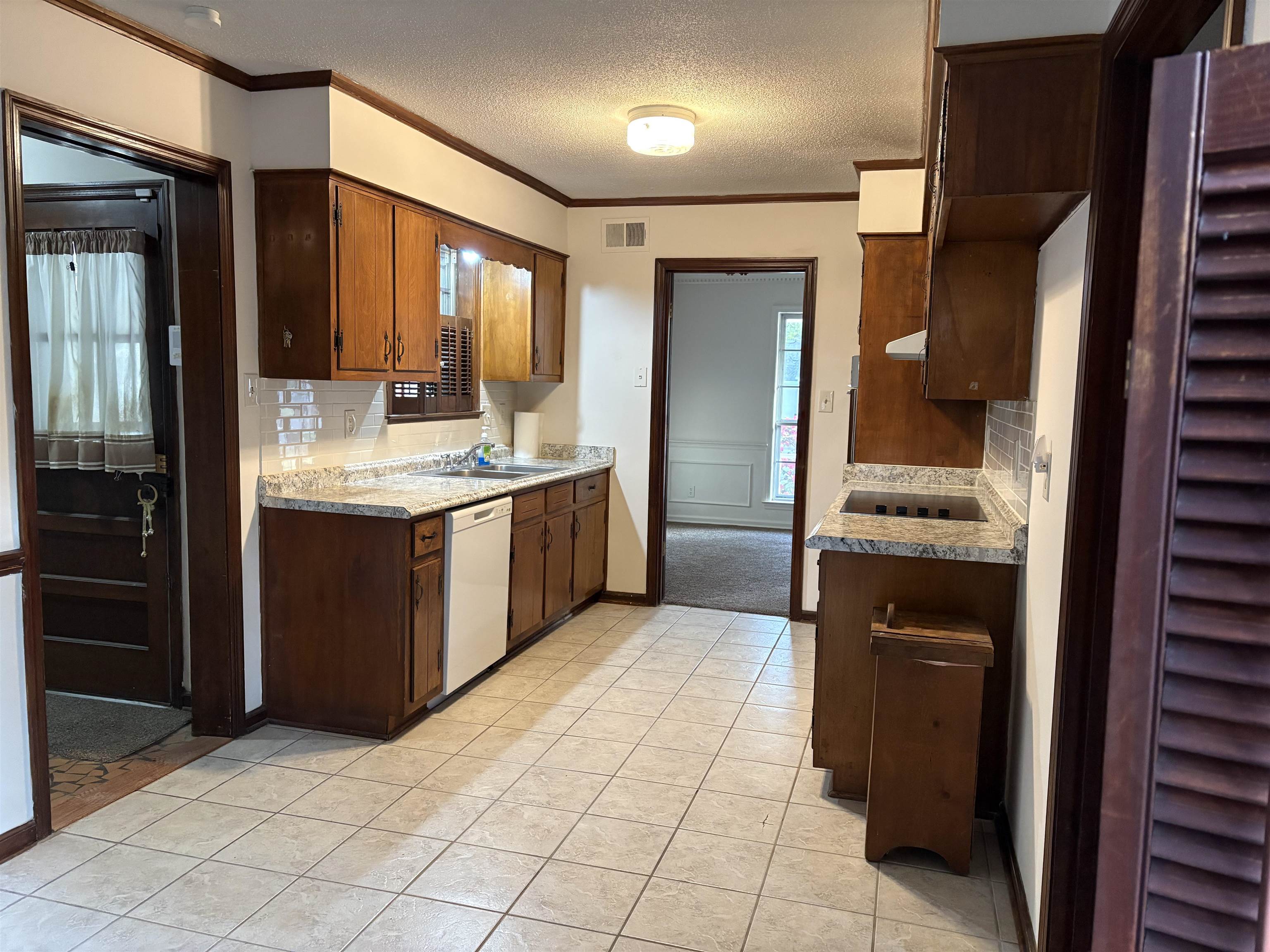 5459 Knight Arnold Road Memphis, TN 38115 - Photo 13 of 38 Kitchen with light countertops, a textured ceiling, ornamental molding, decorative backsplash, and white dishwasher
