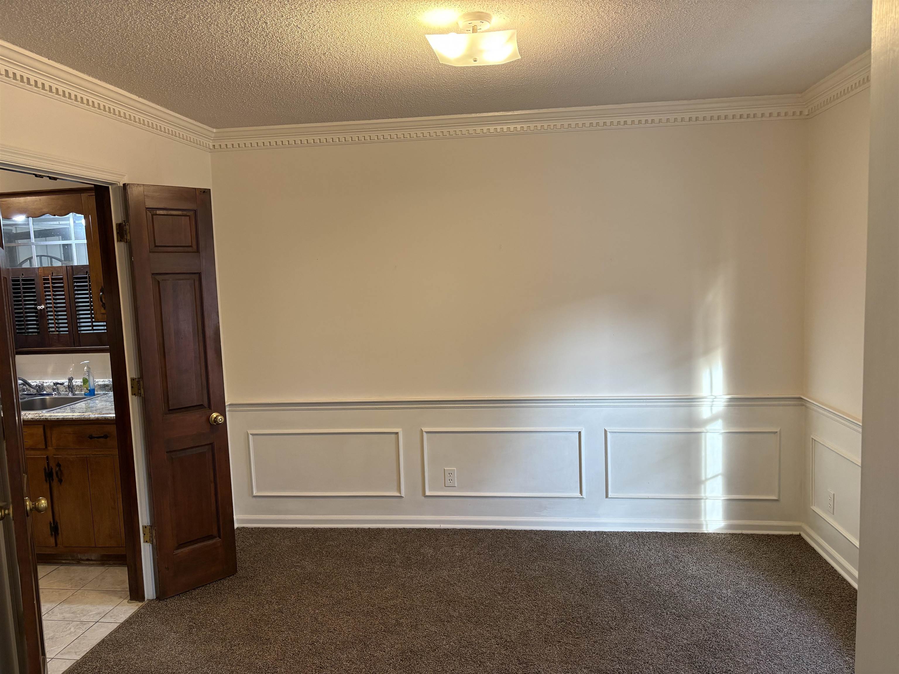 5459 Knight Arnold Road Memphis, TN 38115 - Photo 6 of 38 Spare room with ornamental molding, dark colored carpet, a textured ceiling, wainscoting, and a decorative wall