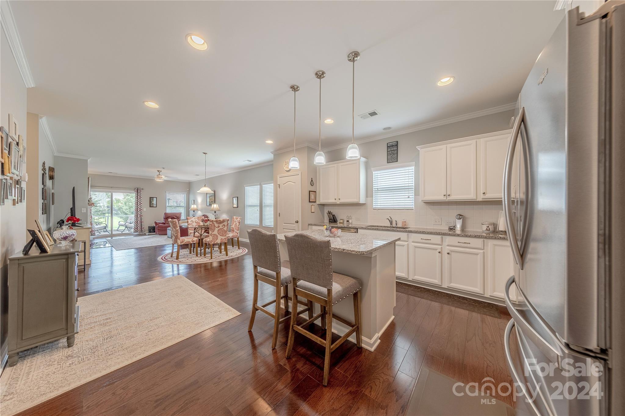 5824 Eleanor Rigby Road Charlotte, NC 28278 - Photo 6 of 34 a kitchen with a dining table chairs refrigerator wooden floor and living room view