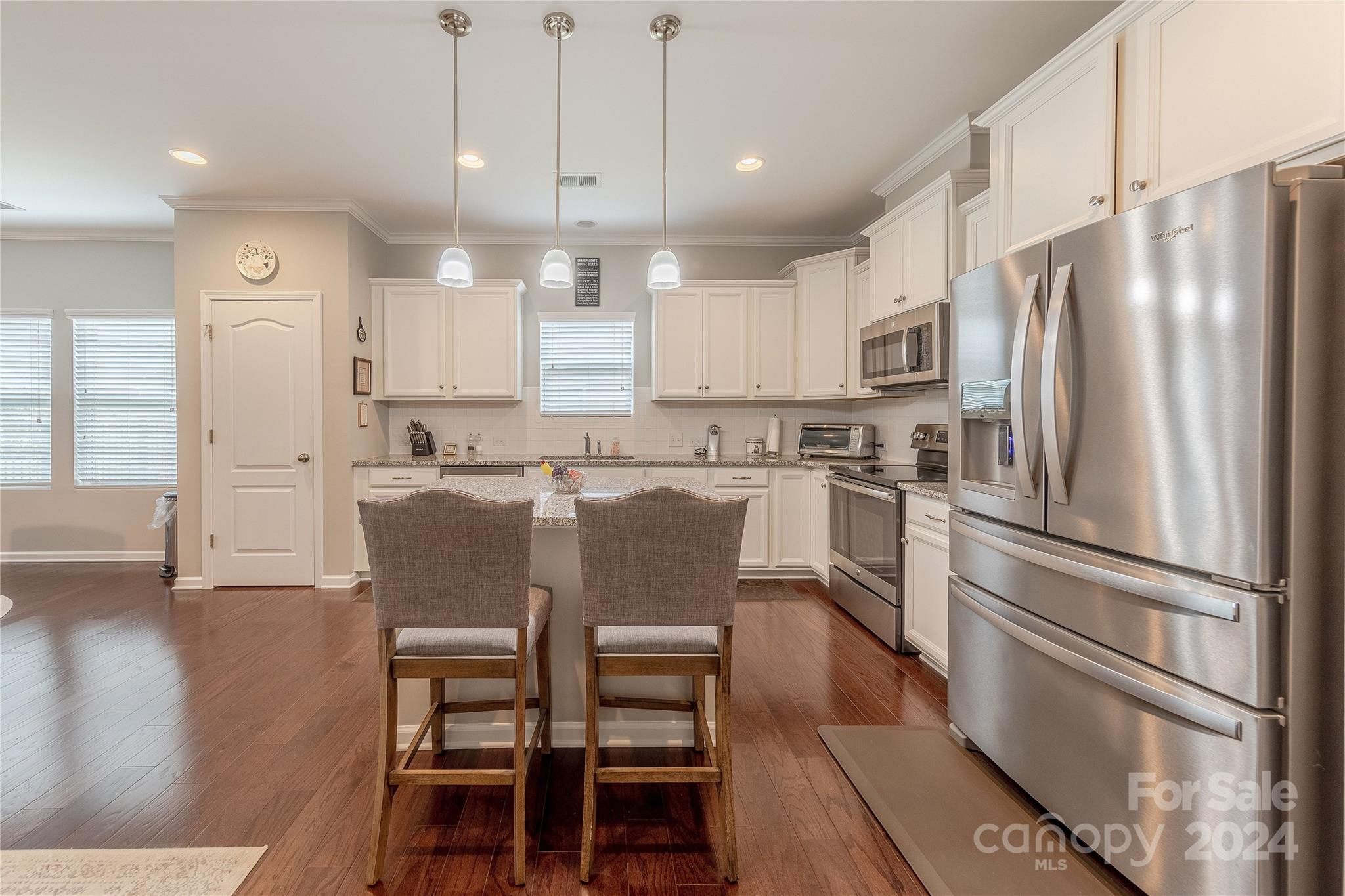 5824 Eleanor Rigby Road Charlotte, NC 28278 - Photo 7 of 34 a kitchen with kitchen island a refrigerator a stove a dining table and chairs with wooden floor