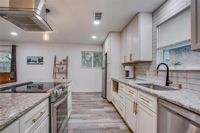 a kitchen with stainless steel appliances granite countertop a sink stove and cabinets