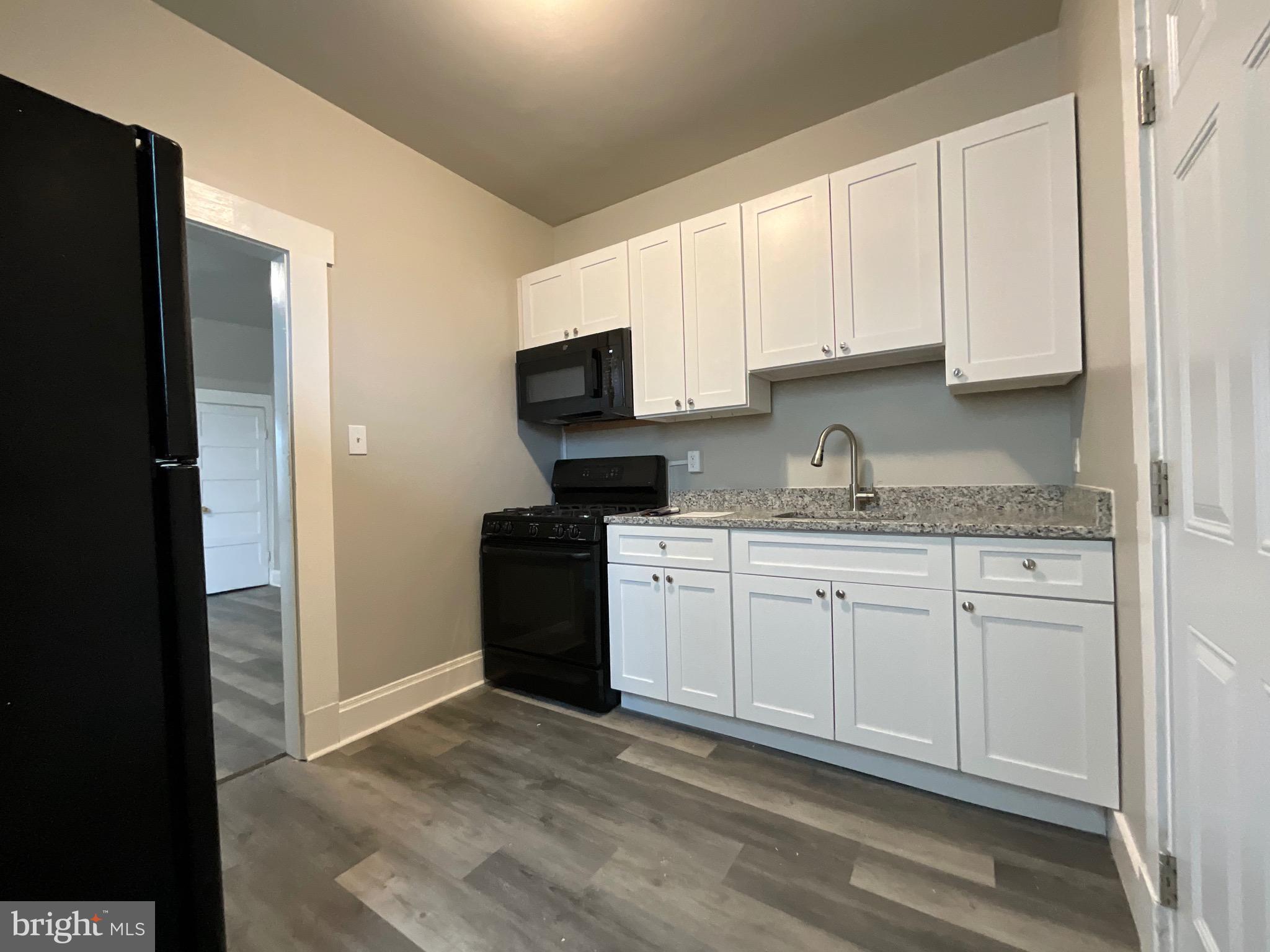 4415 Pimlico Road Baltimore, MD 21215 - Photo 5 of 18 a kitchen with granite countertop white cabinets and refrigerator