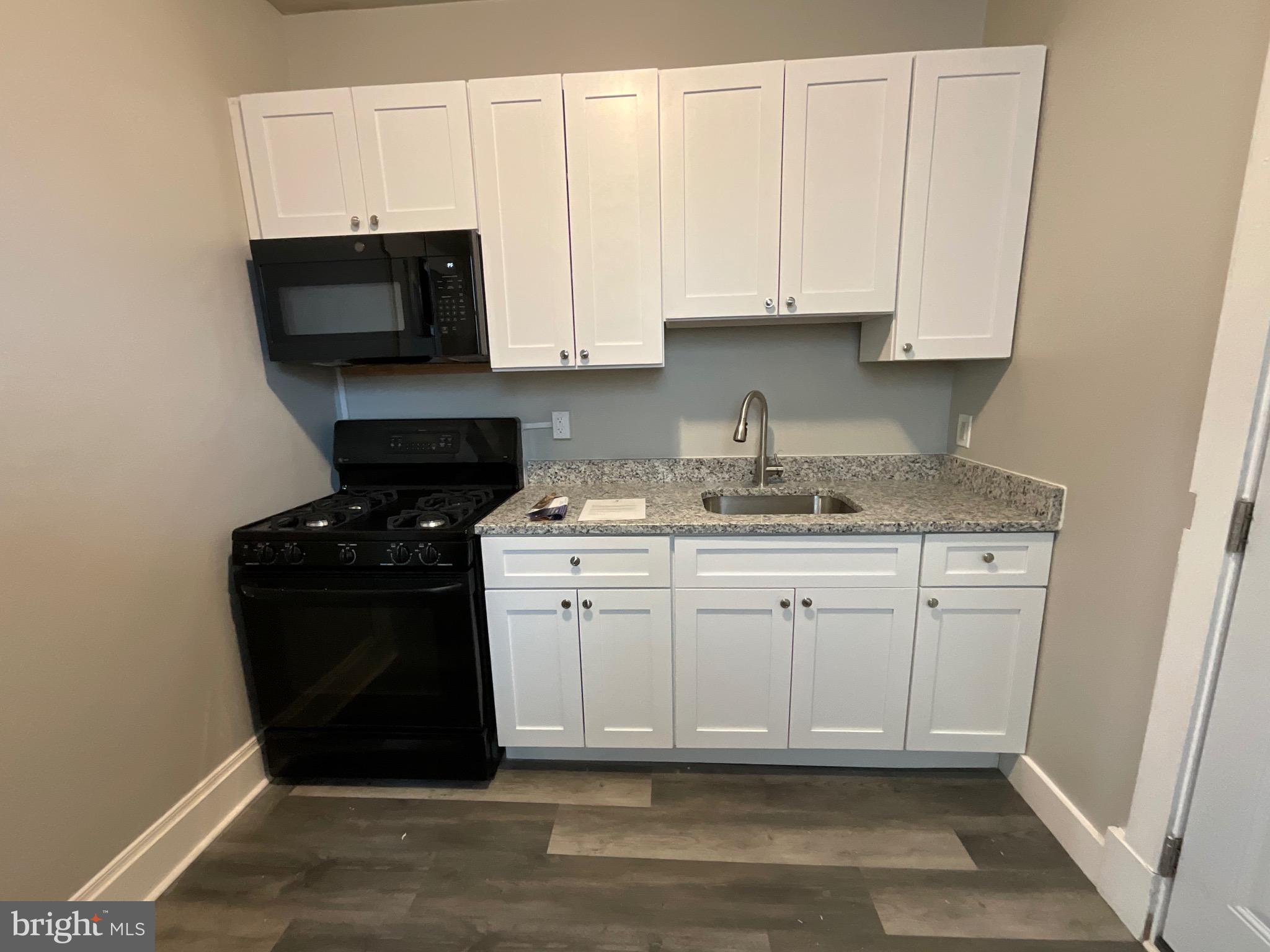 4415 Pimlico Road Baltimore, MD 21215 - Photo 6 of 18 a kitchen with white cabinets and black appliances