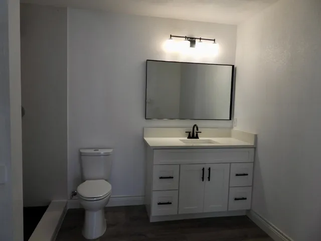 a view of a hallway to room with wooden floor and cabinet