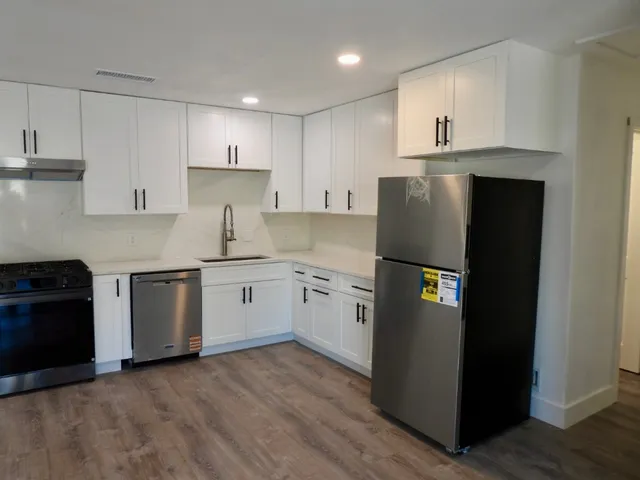 a kitchen with a refrigerator sink and white cabinets