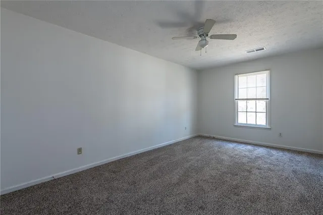 an empty room with a ceiling fan and window