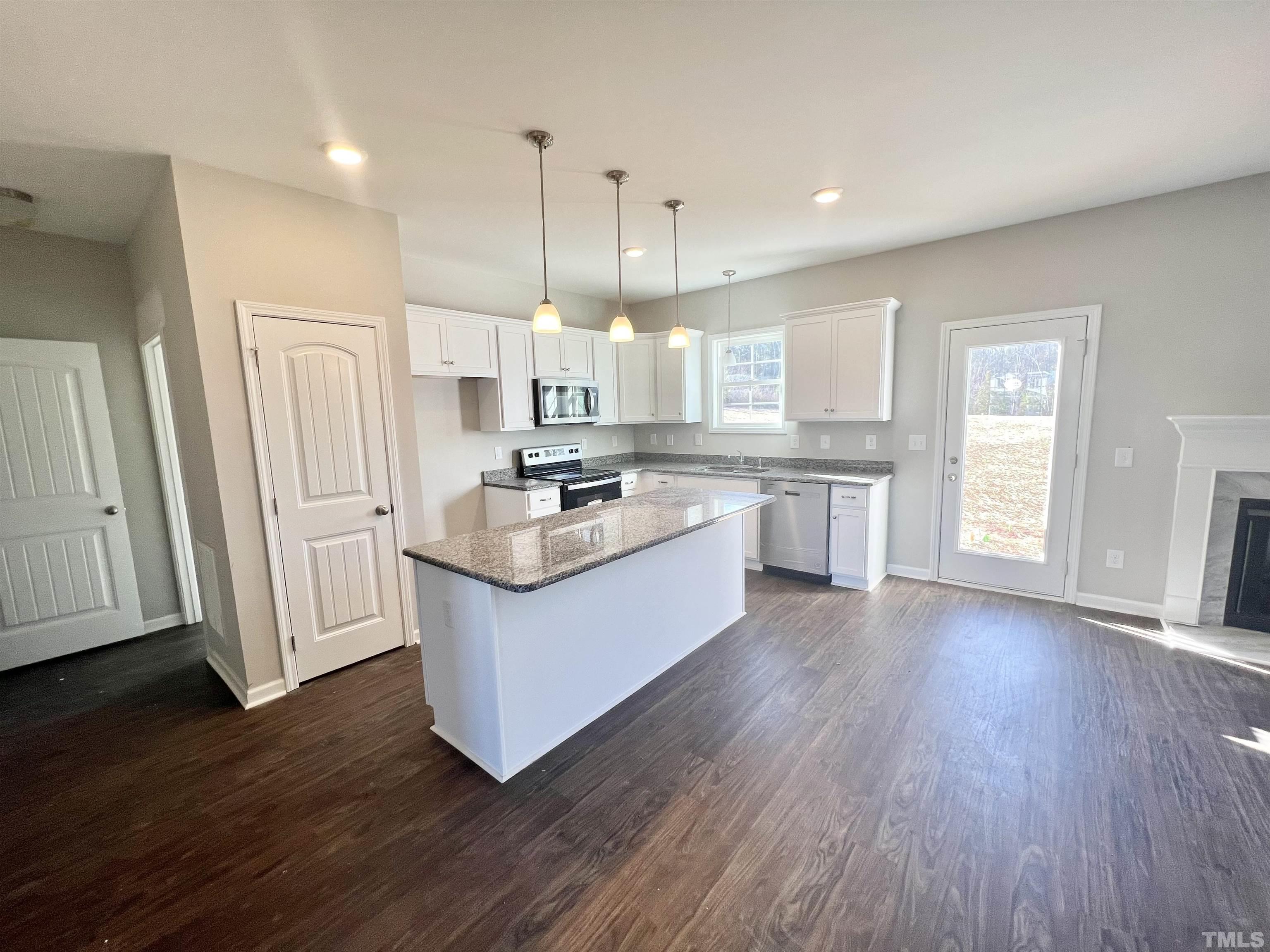 4432 Debnam Road Zebulon, NC 27597 - Photo 4 of 9 a large kitchen with stainless steel appliances granite countertop a stove a sink dishwasher a refrigerator white cabinets and wooden floor next to a window