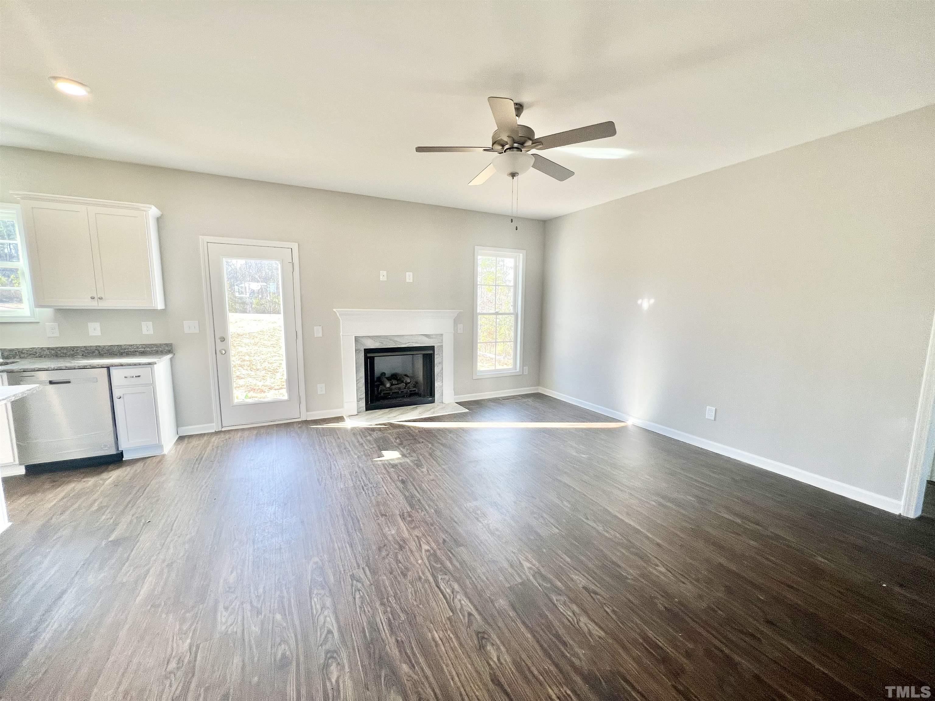4432 Debnam Road Zebulon, NC 27597 - Photo 5 of 9 an empty room with wooden floor fan and windows