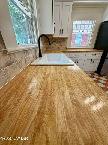 a kitchen with stainless steel appliances granite countertop a sink a stove a refrigerator a counter top space and cabinets