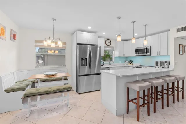 a kitchen with kitchen island granite countertop a refrigerator a stove a sink and a dining table with wooden floor