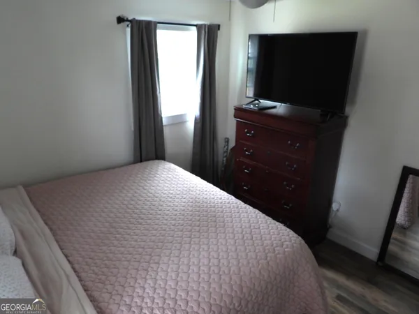 a bedroom with a bed and a flat tv screen on a dresser