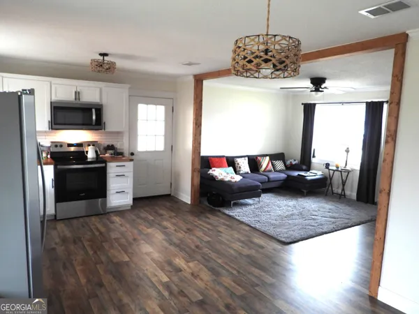 a living room with stainless steel appliances granite countertop a stove refrigerator and microwave