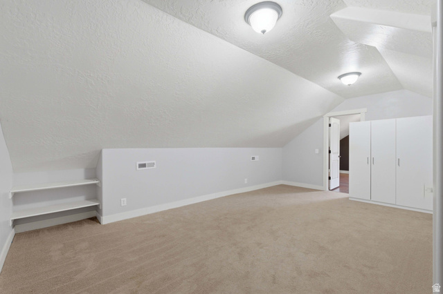2567 West Rim Rock Drive Stockton, UT 84071 - Photo 34 of 64 Carpeted room featuring vaulted ceilings, built-in shelving, white walls, and built-in white cabinetry with silver hardware
