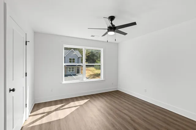 a view of an empty room with a window and wooden floor