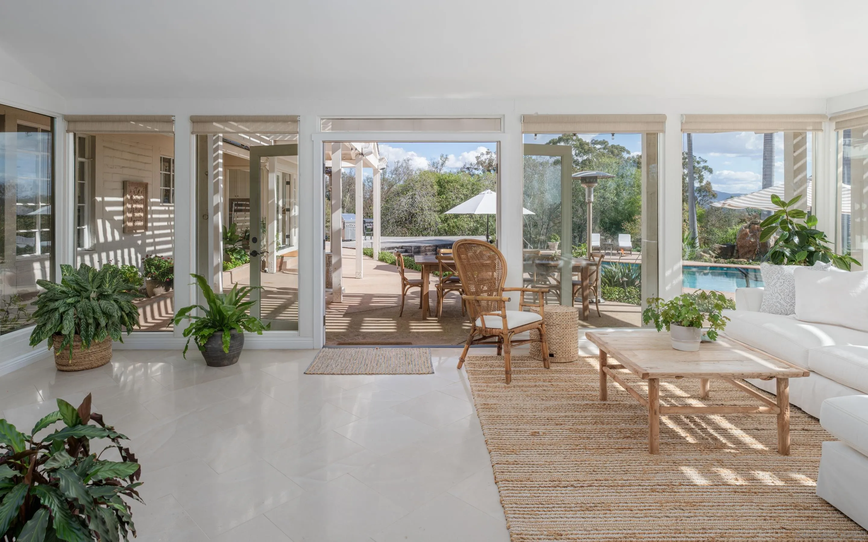 a living room with furniture large windows and plants