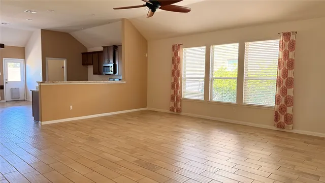 a view of an empty room with a window and wooden floor