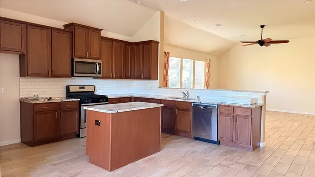 a kitchen with stainless steel appliances granite countertop a stove a sink dishwasher and a microwave oven with cabinets