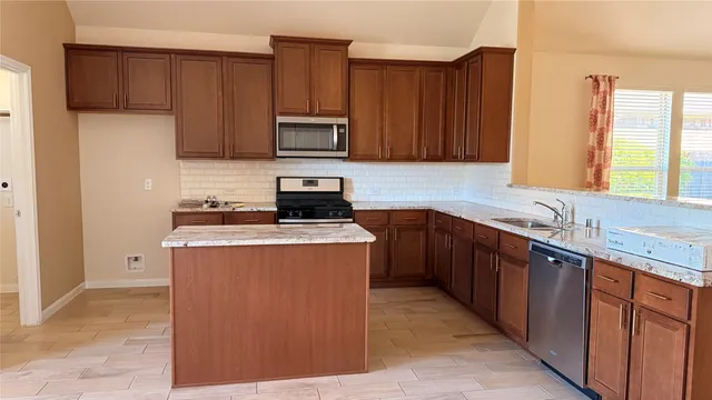 a kitchen with stainless steel appliances granite countertop a stove a sink dishwasher and a refrigerator