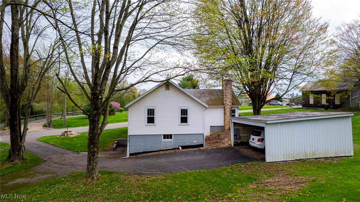 7997 Chestnut Ridge Road Northwest Beach City, OH 44608 - Photo 28 of 31 View of side of home with a chimney, asphalt driveway, a carport, and a yard