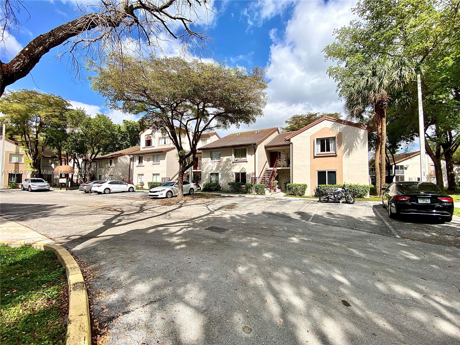 9201 Southwest 138th Place, Unit 9201 Miami, FL 33186 - Photo 14 of 20 a view of road with card parked on side and retail shops