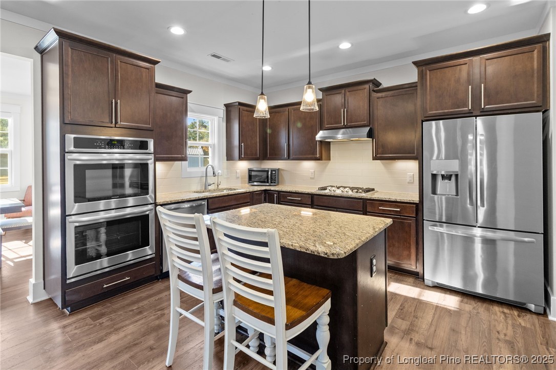 1423 Creekwood Road Hope Mills, NC 28348 - Photo 12 of 49 a kitchen with kitchen island granite countertop stainless steel appliances and wooden cabinets