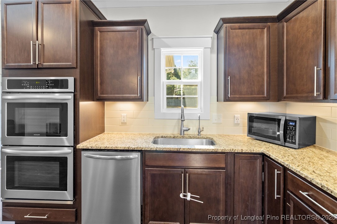 1423 Creekwood Road Hope Mills, NC 28348 - Photo 14 of 49 a kitchen with granite countertop stainless steel appliances wooden cabinets a stove and a refrigerator