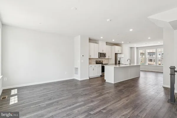 a large kitchen with stainless steel appliances kitchen island a large counter top and a wooden floors