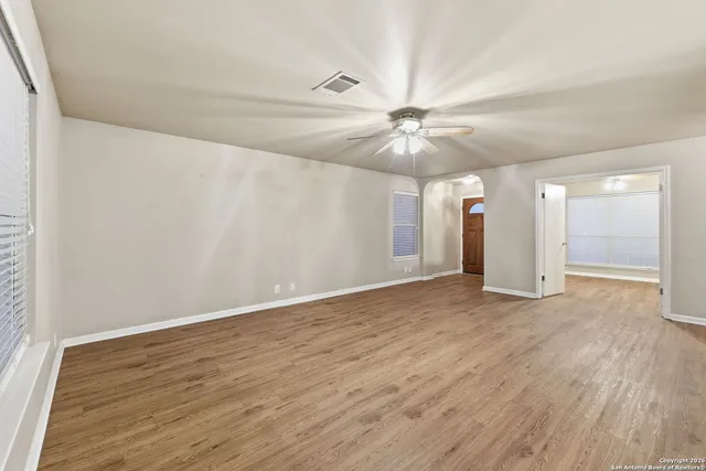 an empty room with wooden floor and fan