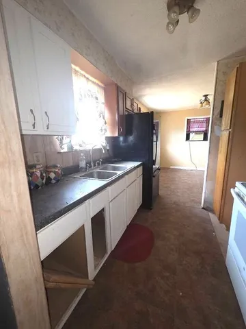 a kitchen with granite countertop a refrigerator and white cabinets