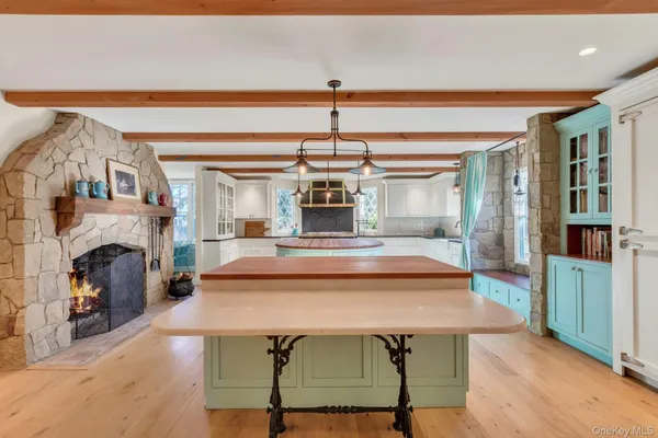 a view of a dining room with furniture wooden floor fireplace and a chandelier