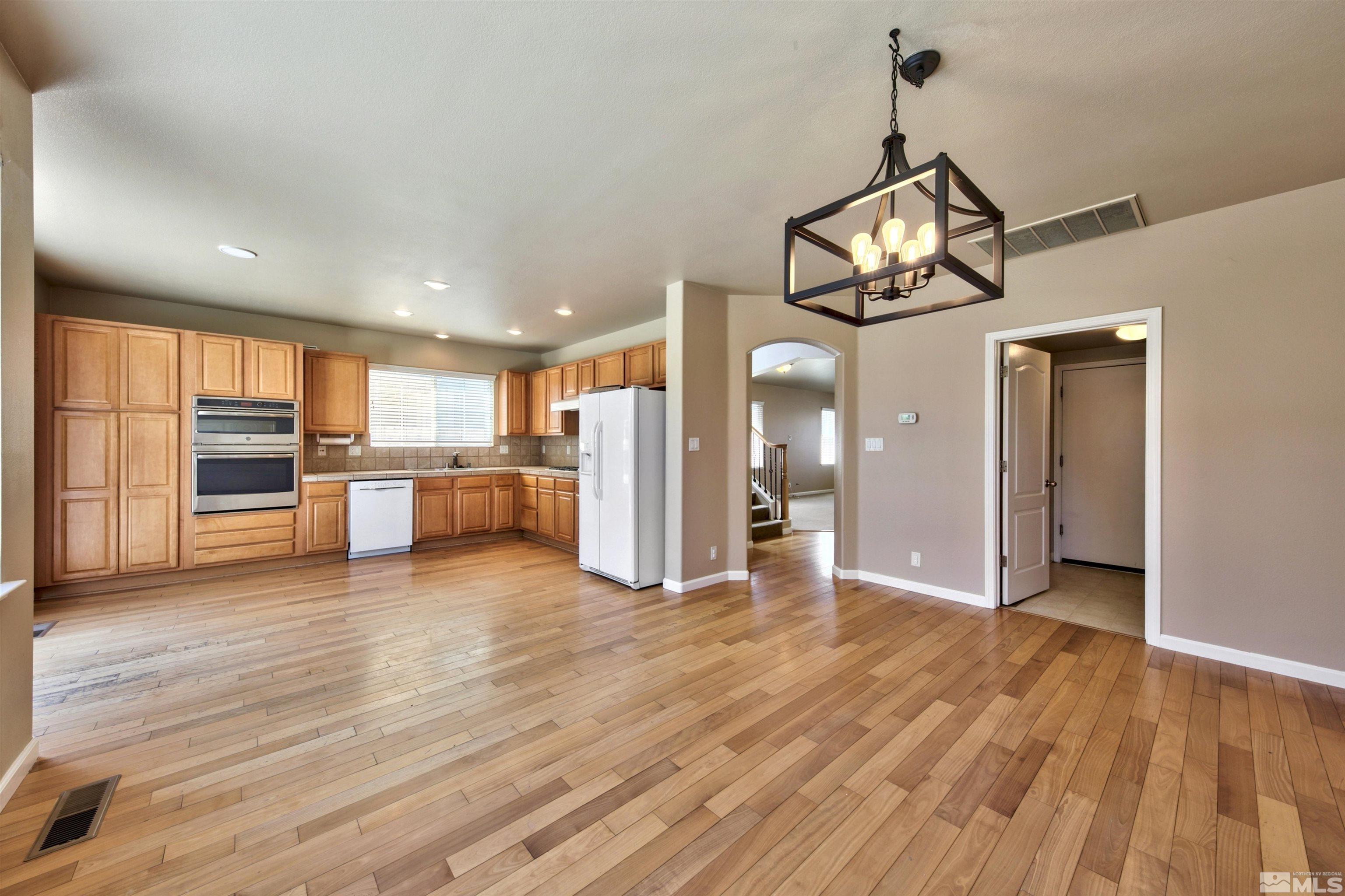 10084 Silver Star Drive Reno, NV 89521 - Photo 5 of 26 a view of a kitchen with a refrigerator wooden floor and a ceiling fan
