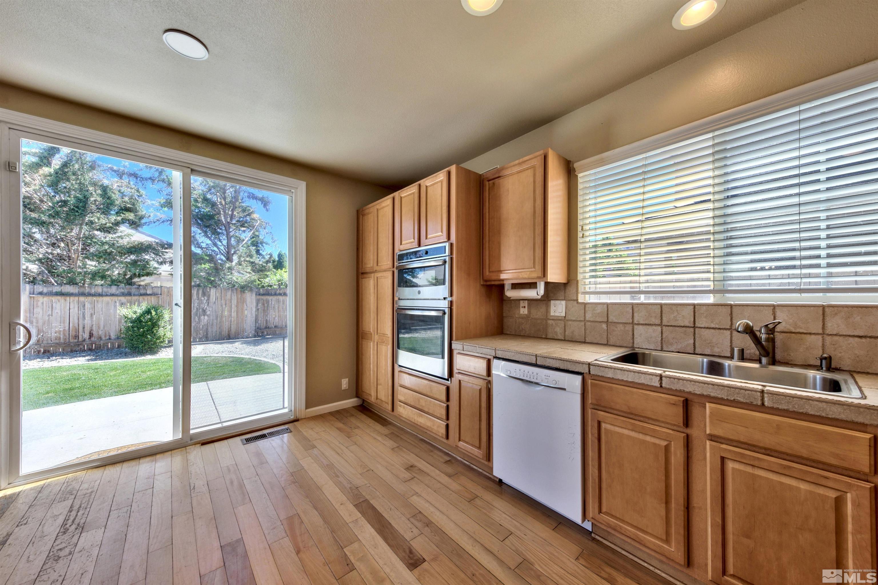 10084 Silver Star Drive Reno, NV 89521 - Photo 7 of 26 a kitchen with stainless steel appliances granite countertop wooden floors and sink