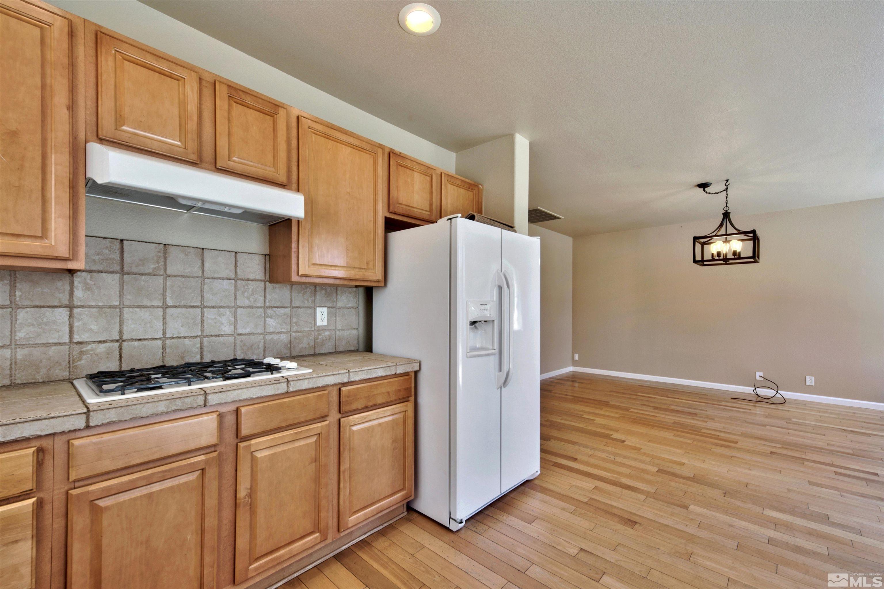 10084 Silver Star Drive Reno, NV 89521 - Photo 8 of 26 a kitchen with a refrigerator a stove and wooden cabinets